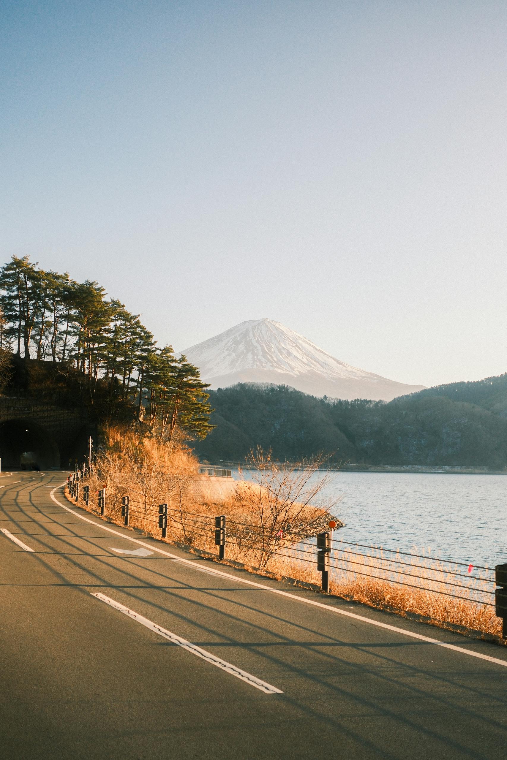 Beautiful view of Mount Fuji from a lakeside road in Fujikawaguchiko, Japan, during a serene day.